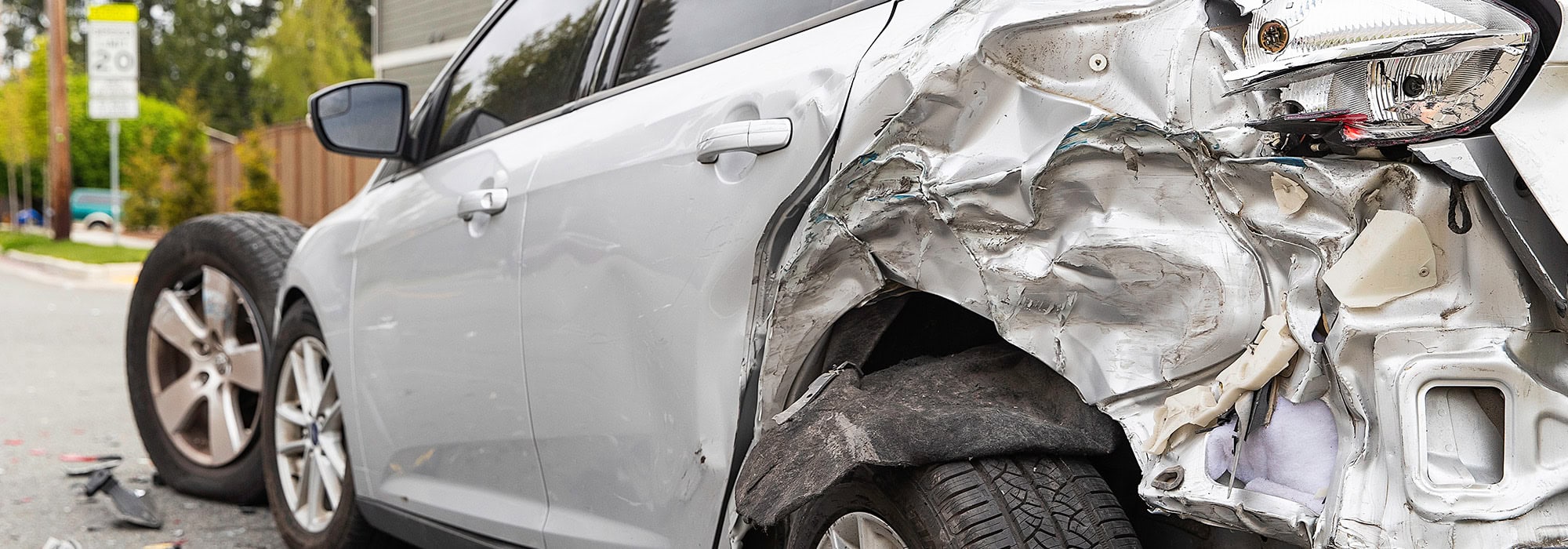 Severely damaged car that was hit in the rear on the side of a road